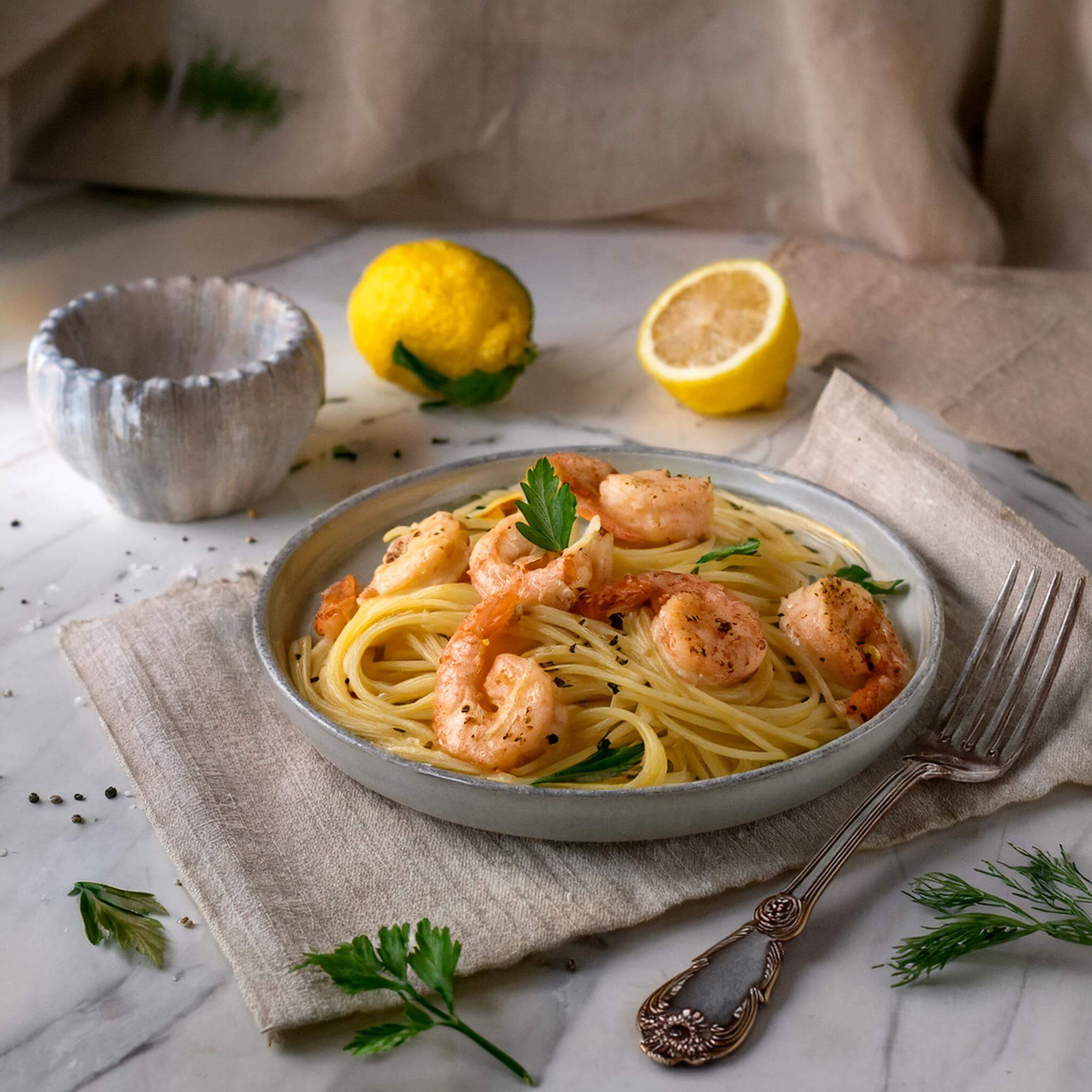 Lemon butter garlic shrimp pasta served on a table with white wine.