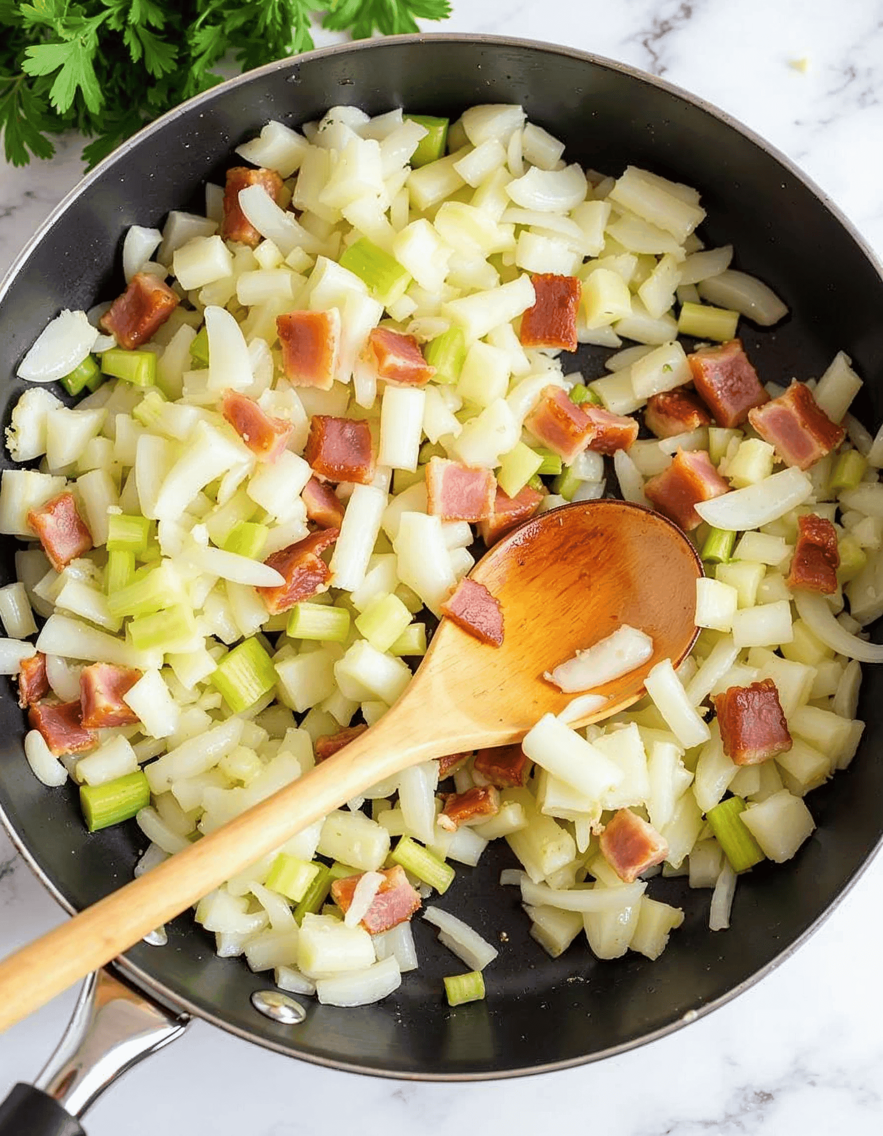 Onions, celery, and garlic sautéing in butter in a skillet.