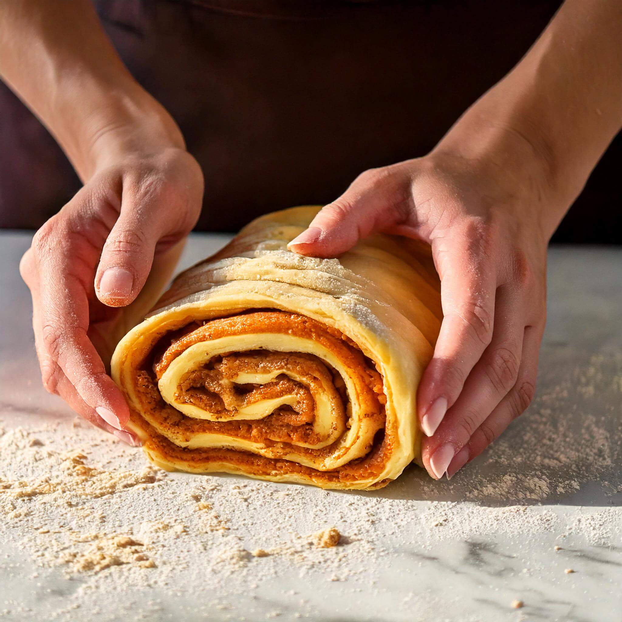 Twisting pumpkin spice babka dough with visible swirls.