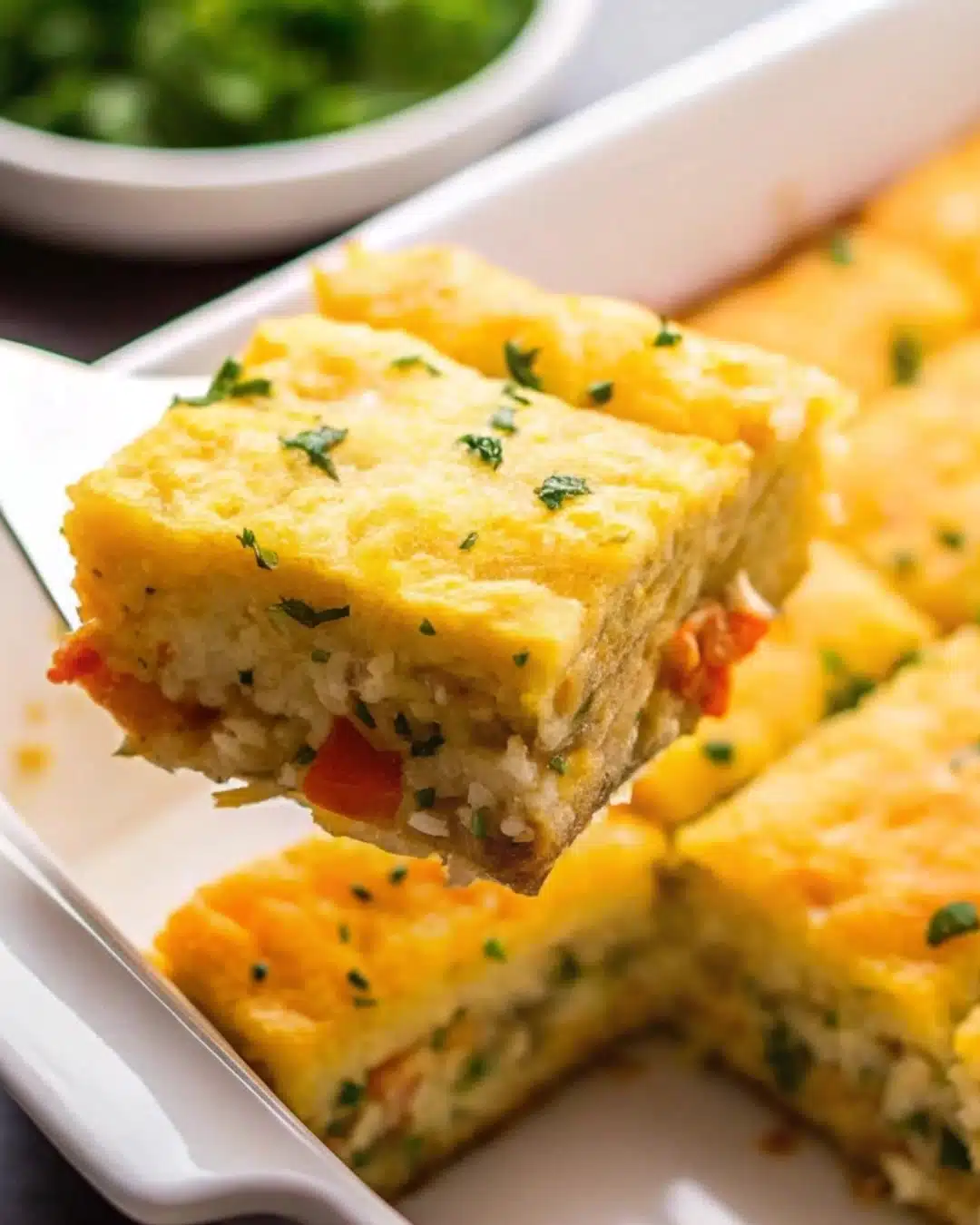 Serving a slice of Tater Tot breakfast casserole on a plate.