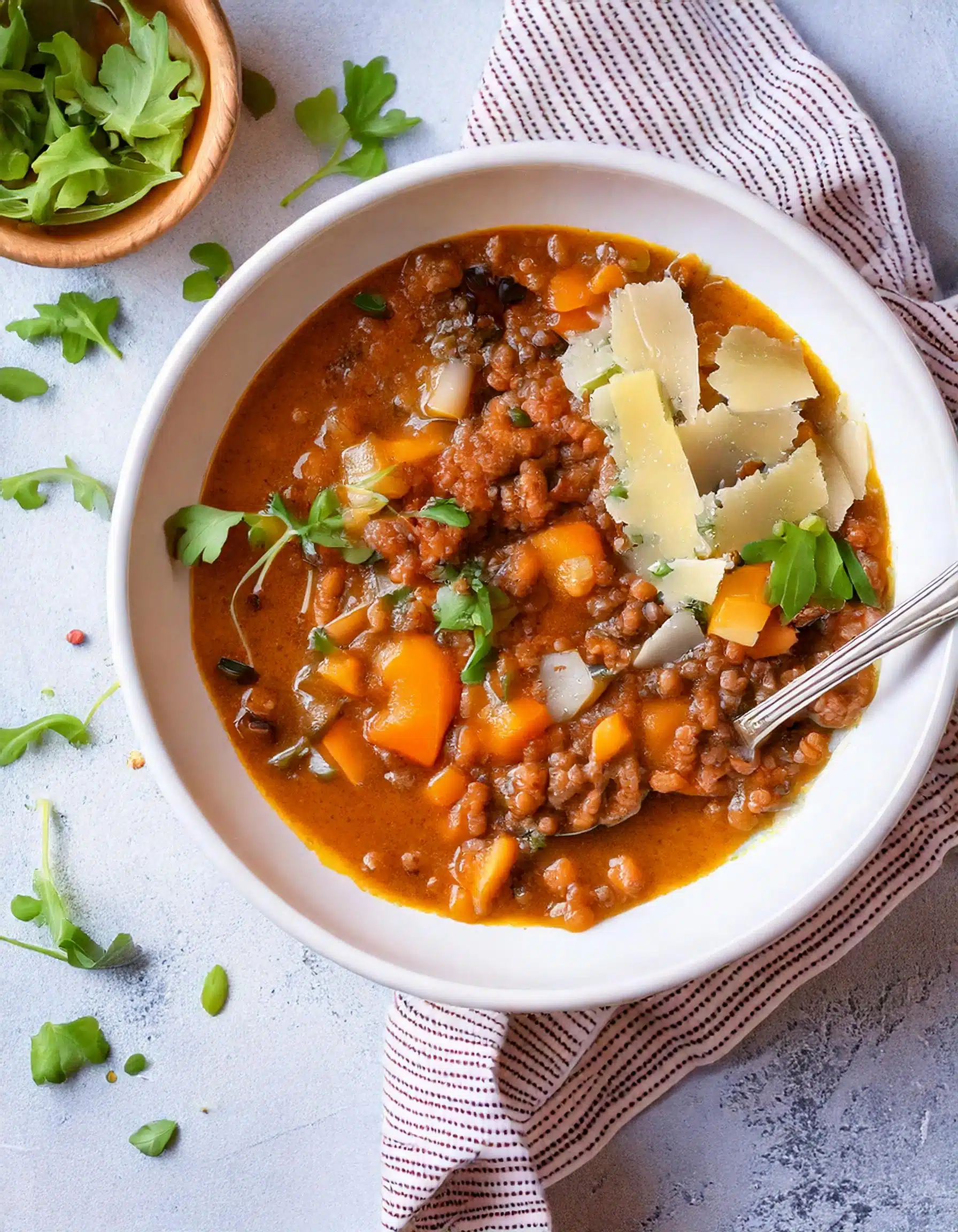 Bowl of lentil soup with cheese and fresh herbs.