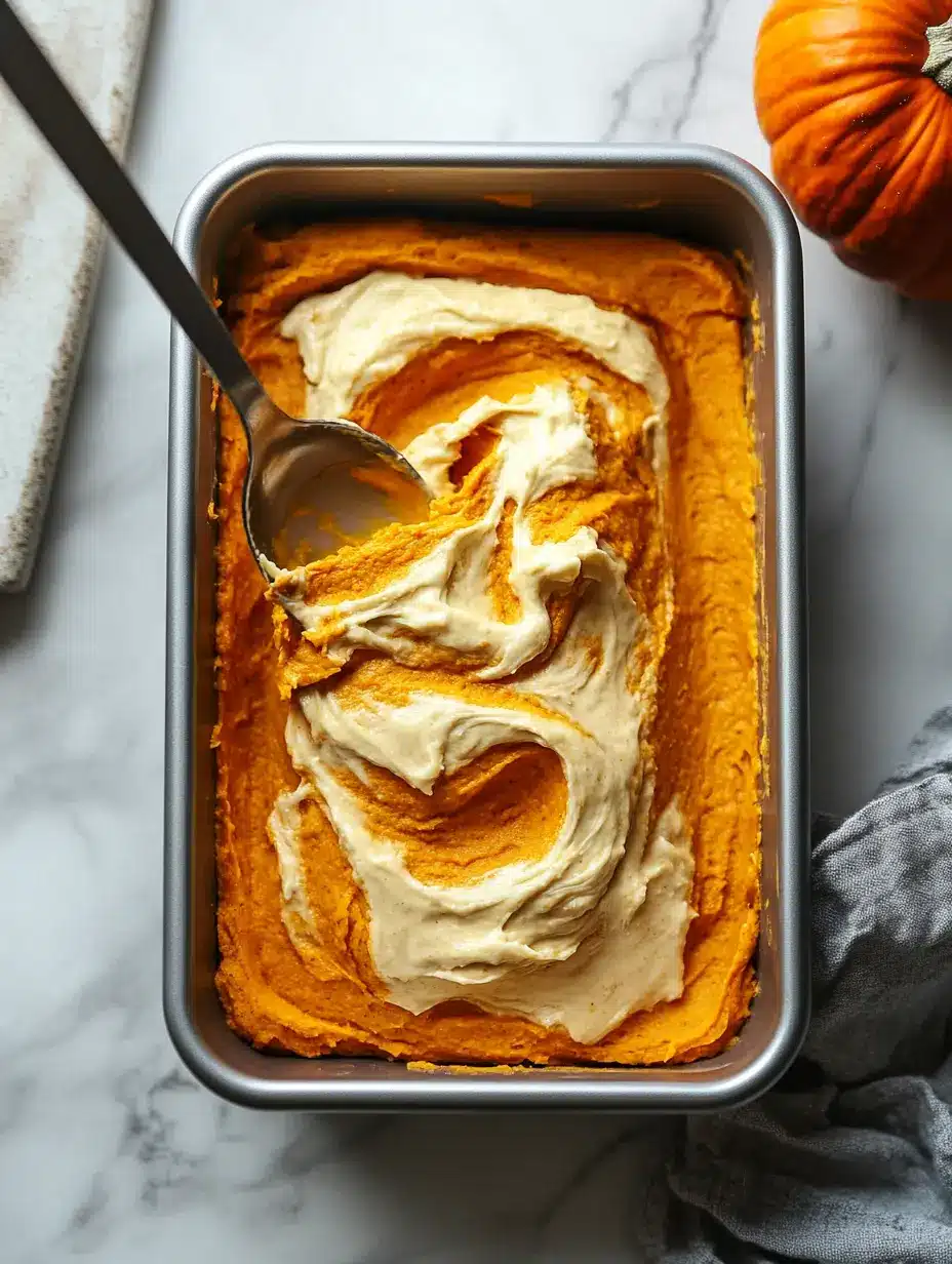Pumpkin bread batter swirled with cheesecake layer in a loaf pan